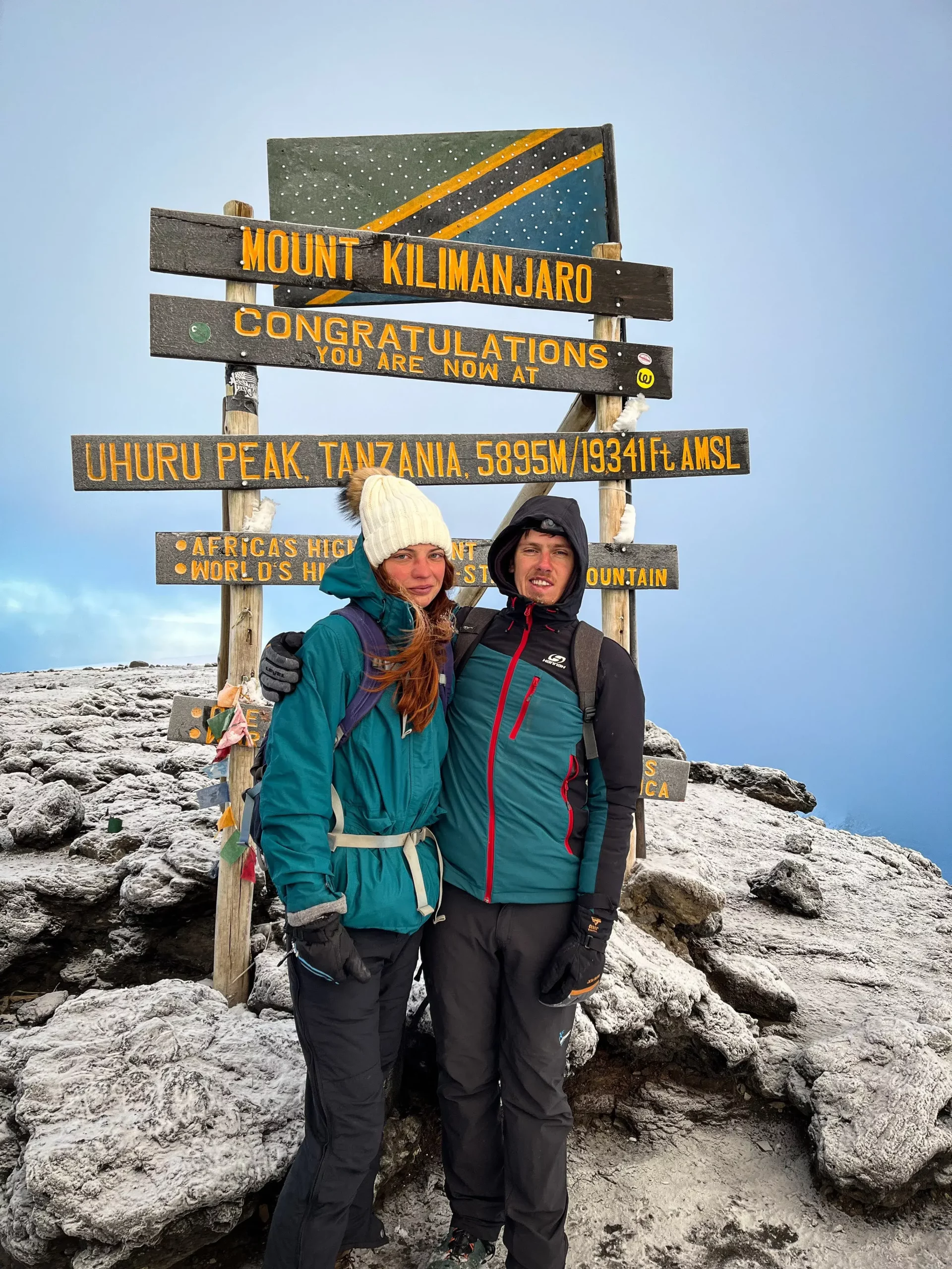 Our travelers who are couple taking a picture with the Kilimanjaro summit at uhuru peak