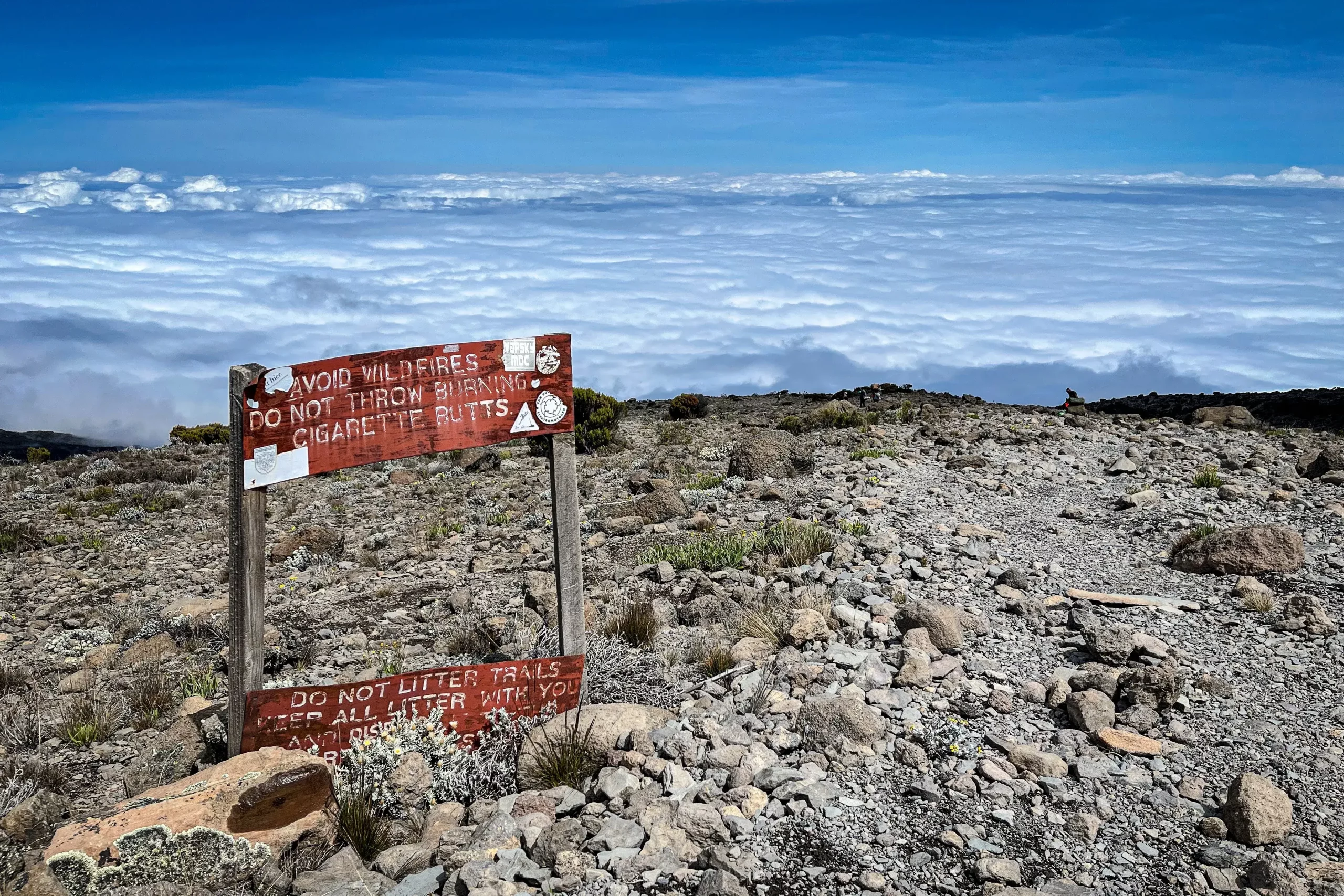 the magnificent view of snow and clouds along with caution board at Kilimanjaro peak after trekking for 5 days